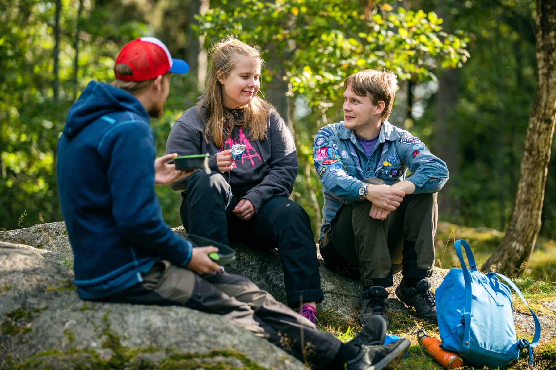tre personer sitter på en sten