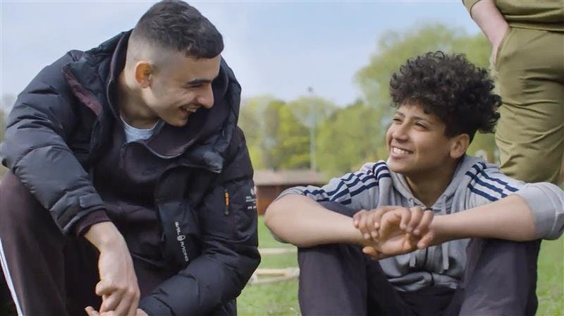 Två ungdomar ler mot varandra
