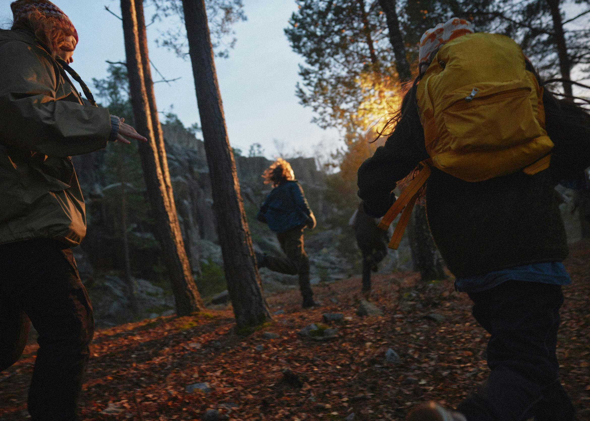 Scouter springer i en grön skog