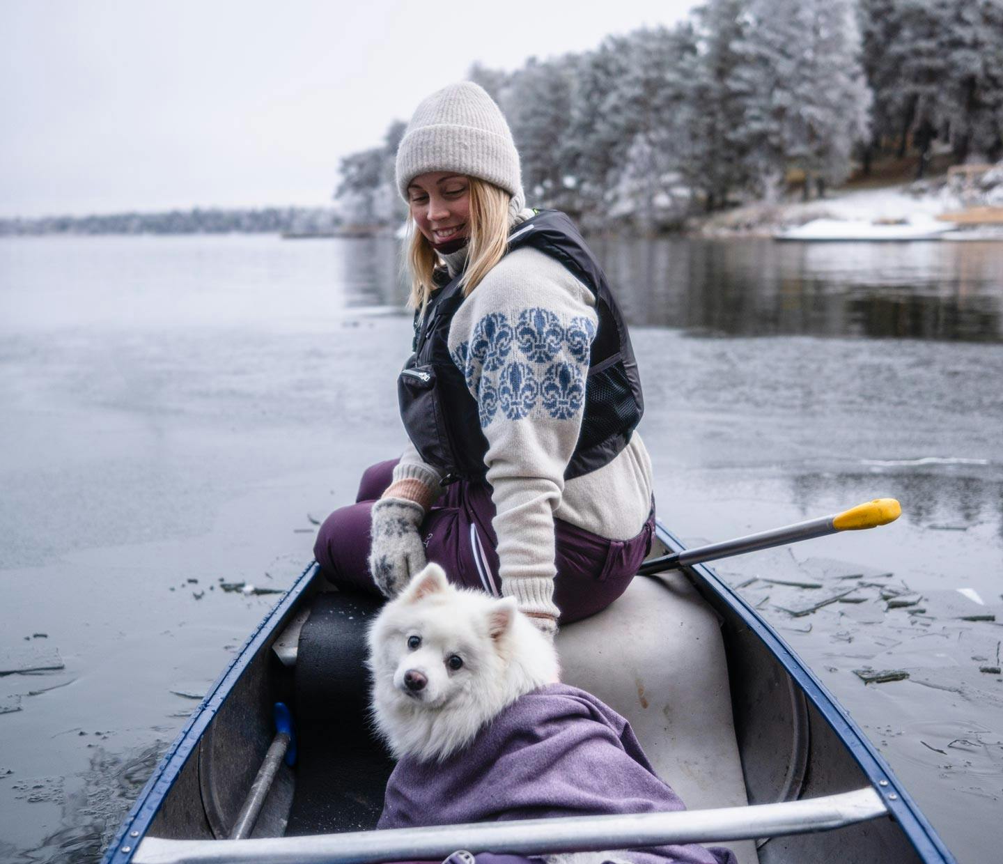Paddlar kanot med hund i ett vinterlandskap