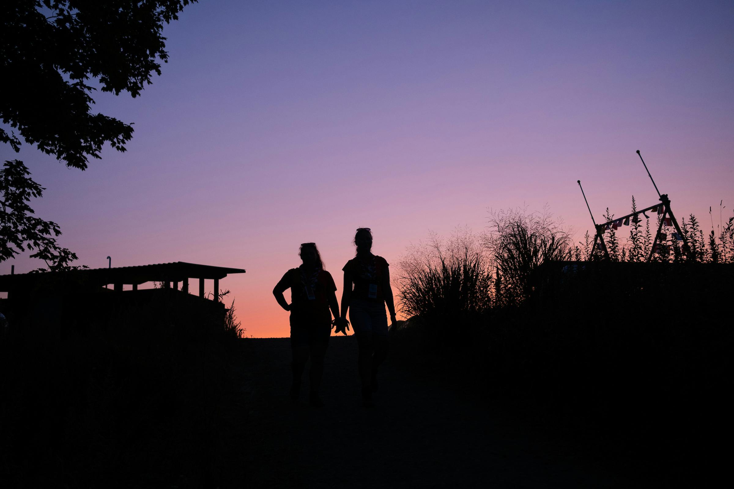 Två personer håller handen i solnedgången utomhus