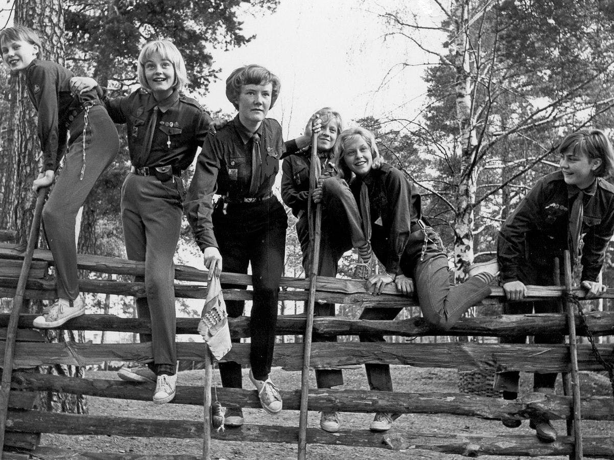 En grupp flickor på 50-talet klättrar över ett staket.